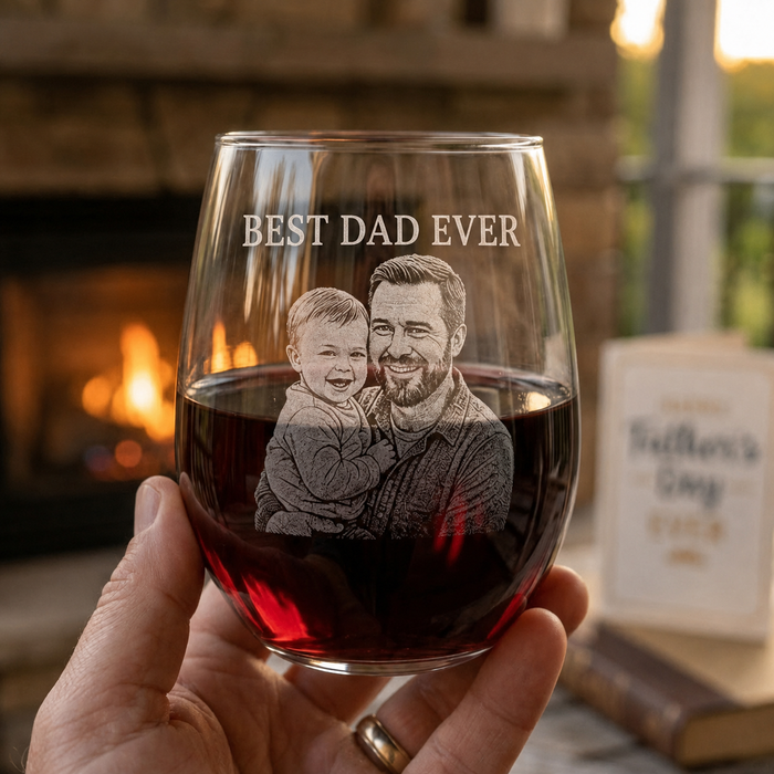 Custom engraved photo wine glass with Best Dad Ever portrait design, shown with red wine in a cozy fireplace setting.