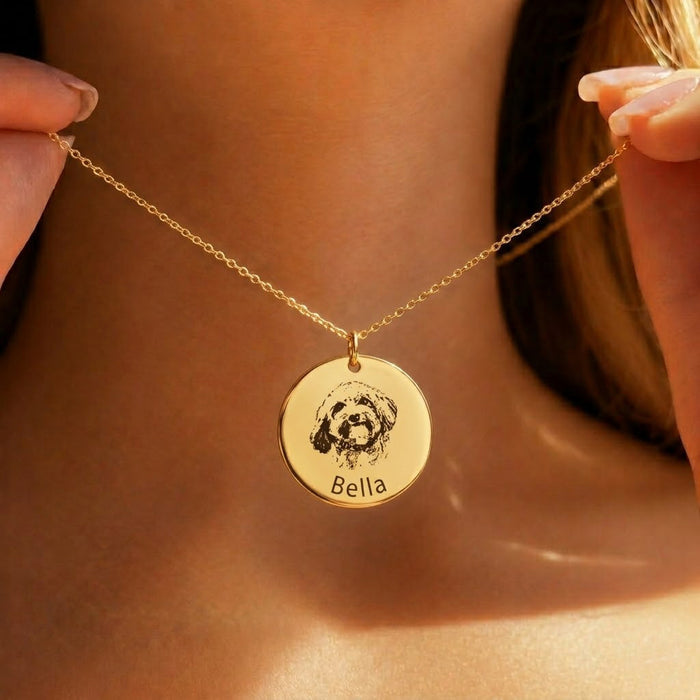 Woman wearing a gold custom pet portrait necklace engraved from a real dog photo with the name Bella on a round pendant.