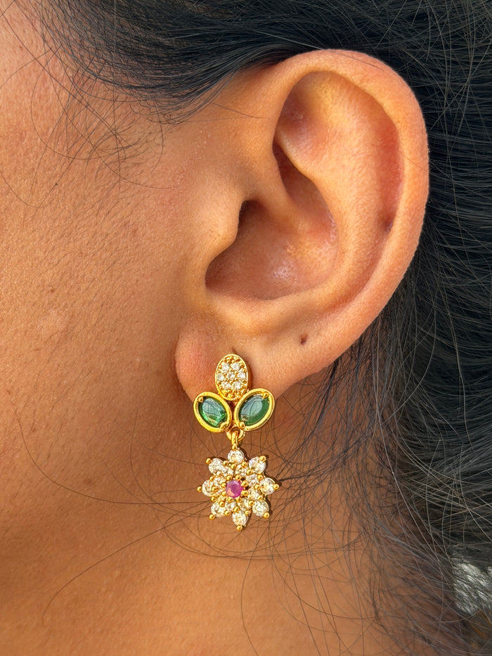 gold earring with green and red gemstones.