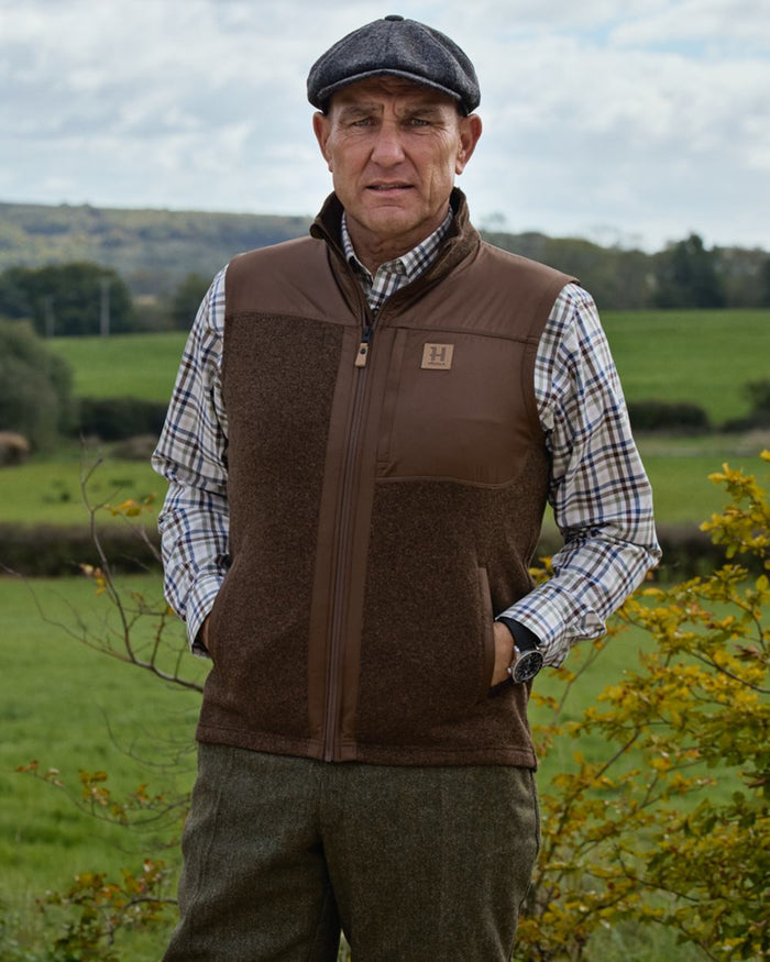 Dark Earth coloured Harkila Mens Kalix Fleece Waistcoat on outdoor background #colour_dark-earth