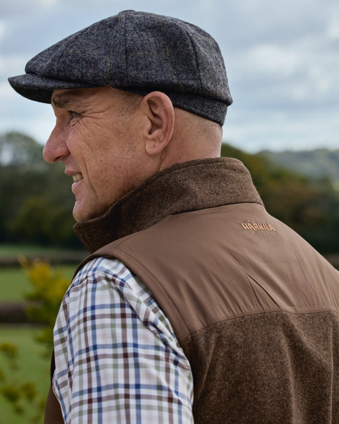 Dark Earth coloured Harkila Mens Kalix Fleece Waistcoat on outdoor background #colour_dark-earth