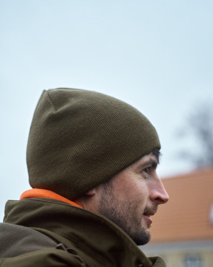 Willow Green Orange Coloured Harkila Reversible Beanie on outdoor background #colour_willow-green-orange