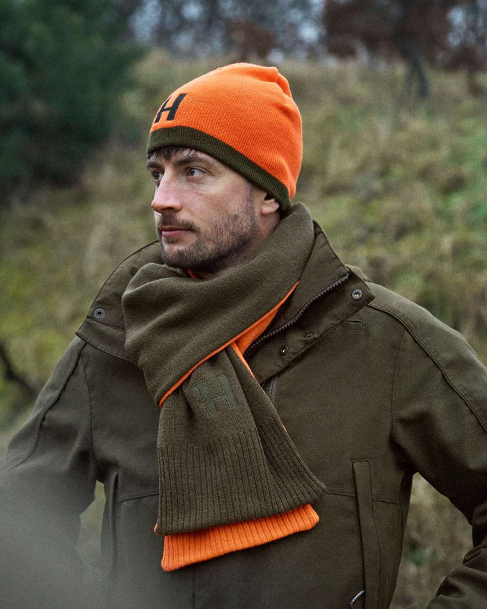 Willow Green Orange Coloured Harkila Reversible Beanie on outdoor background #colour_willow-green-orange