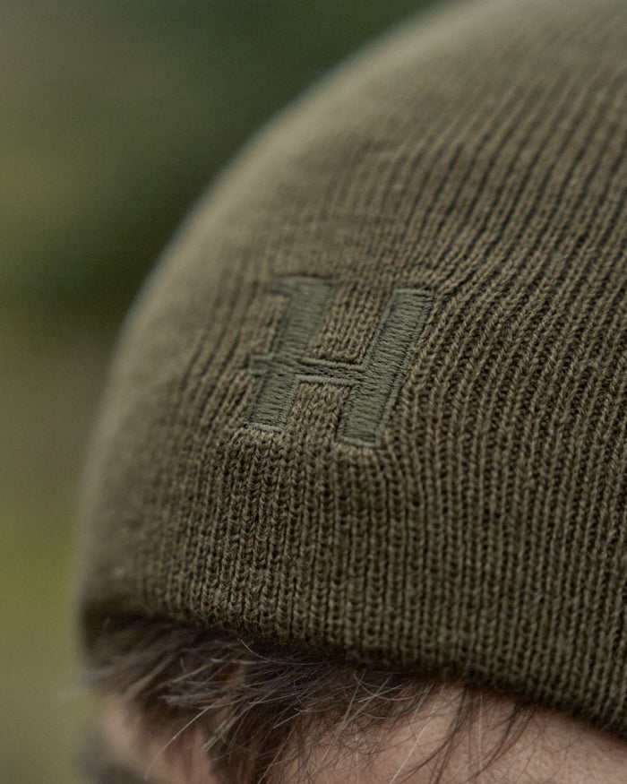 Willow Green Orange Coloured Harkila Reversible Beanie on outdoor background #colour_willow-green-orange