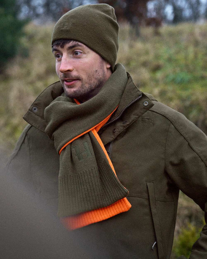 Willow Green Orange Coloured Harkila Reversible Scarf on outdoor background #colour_willow-green-orange