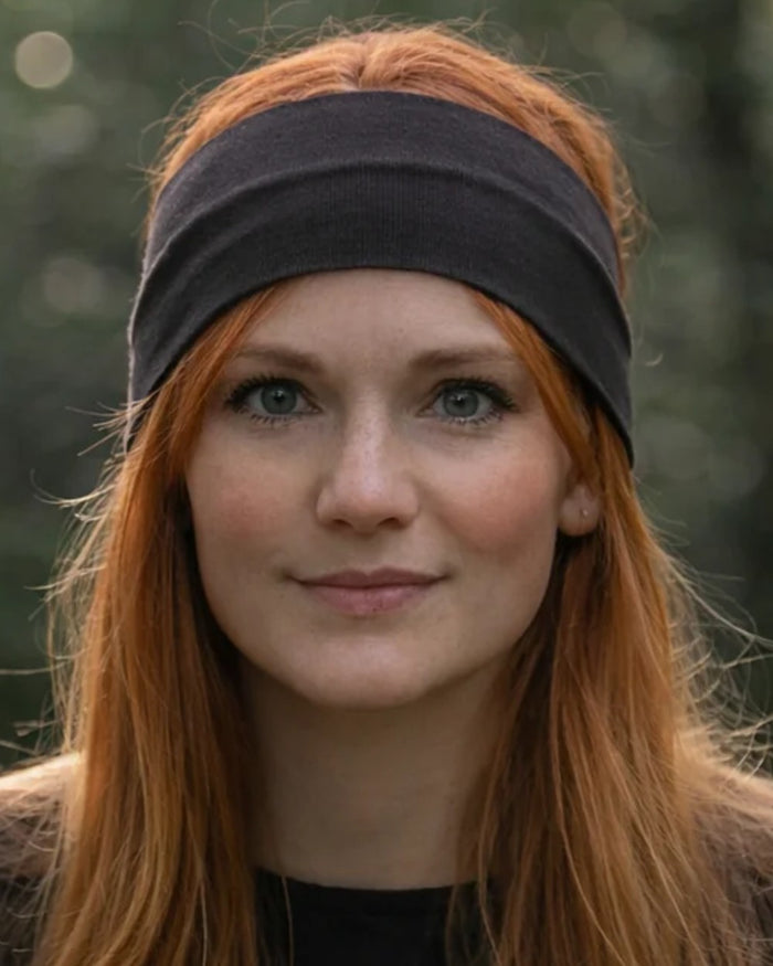Dark Green coloured Northern Hunting Norr Rak Merino Headband on forest background #colour_dark-green