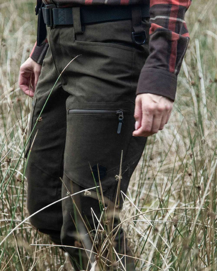 Dark Green coloured Northern Hunting Womens Alva Una G2 Hunting Trousers on forest background #colour_dark-green