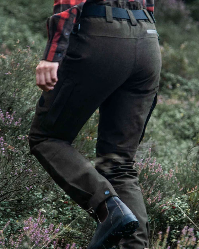 Dark Green coloured Northern Hunting Womens Alva Una G2 Hunting Trousers on forest background #colour_dark-green