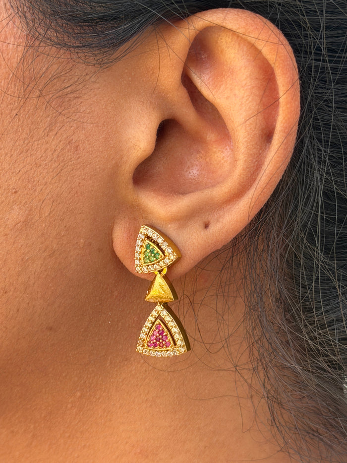 ear wearing a gold and gemstone earring.