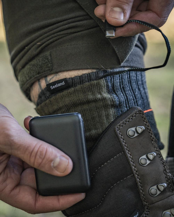 Pine Green Melange coloured Seeland Celsius Heat Socks on forest background #colour_pine-green-melange